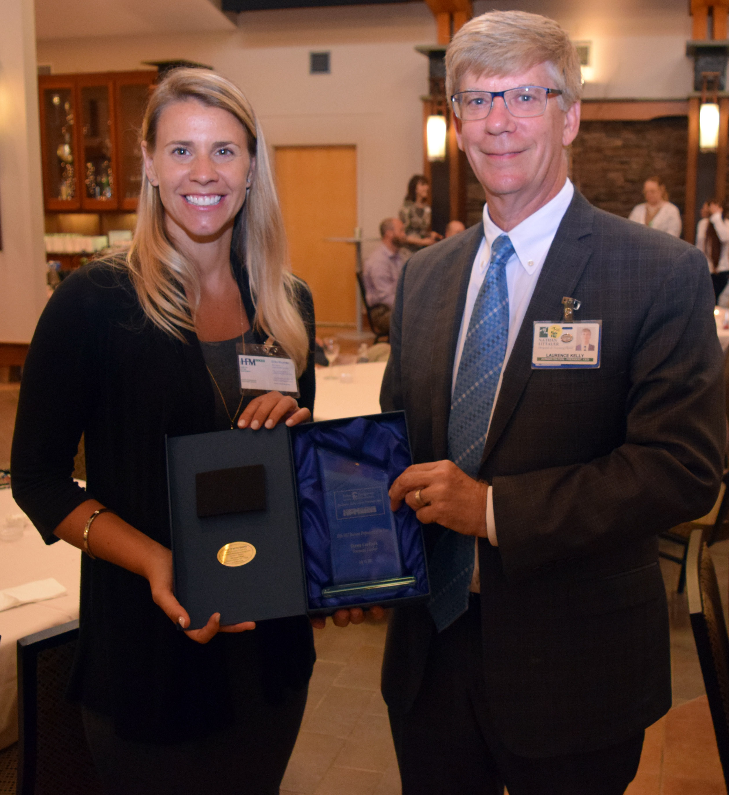 two people pose for a photo holding a prize.