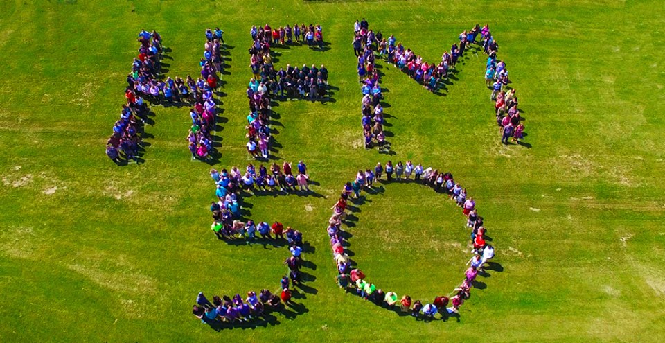 people stand on a lawn spelling out HFM 50 for a photo taken by a drone.
