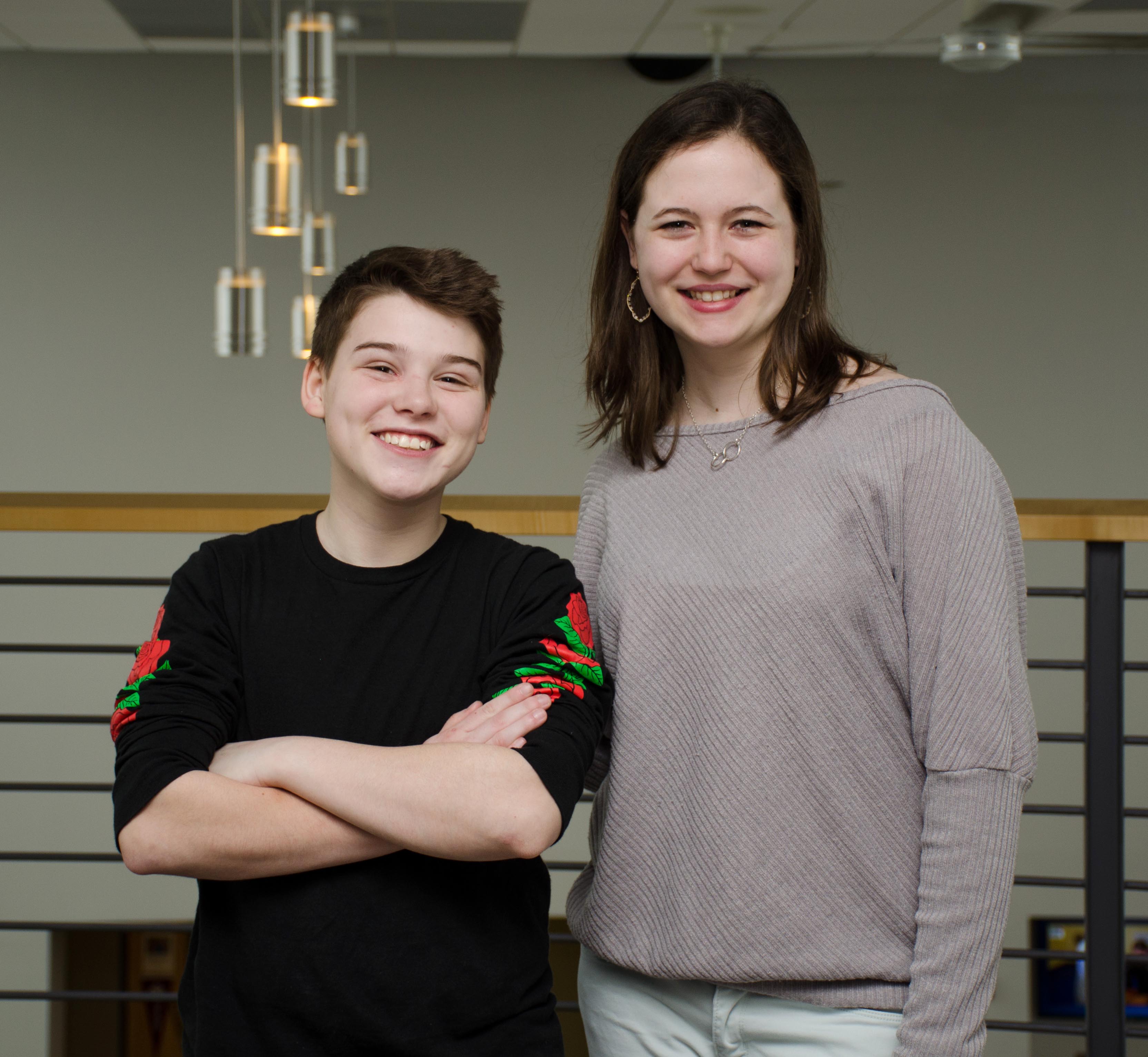 Two students stand side by side smiling.