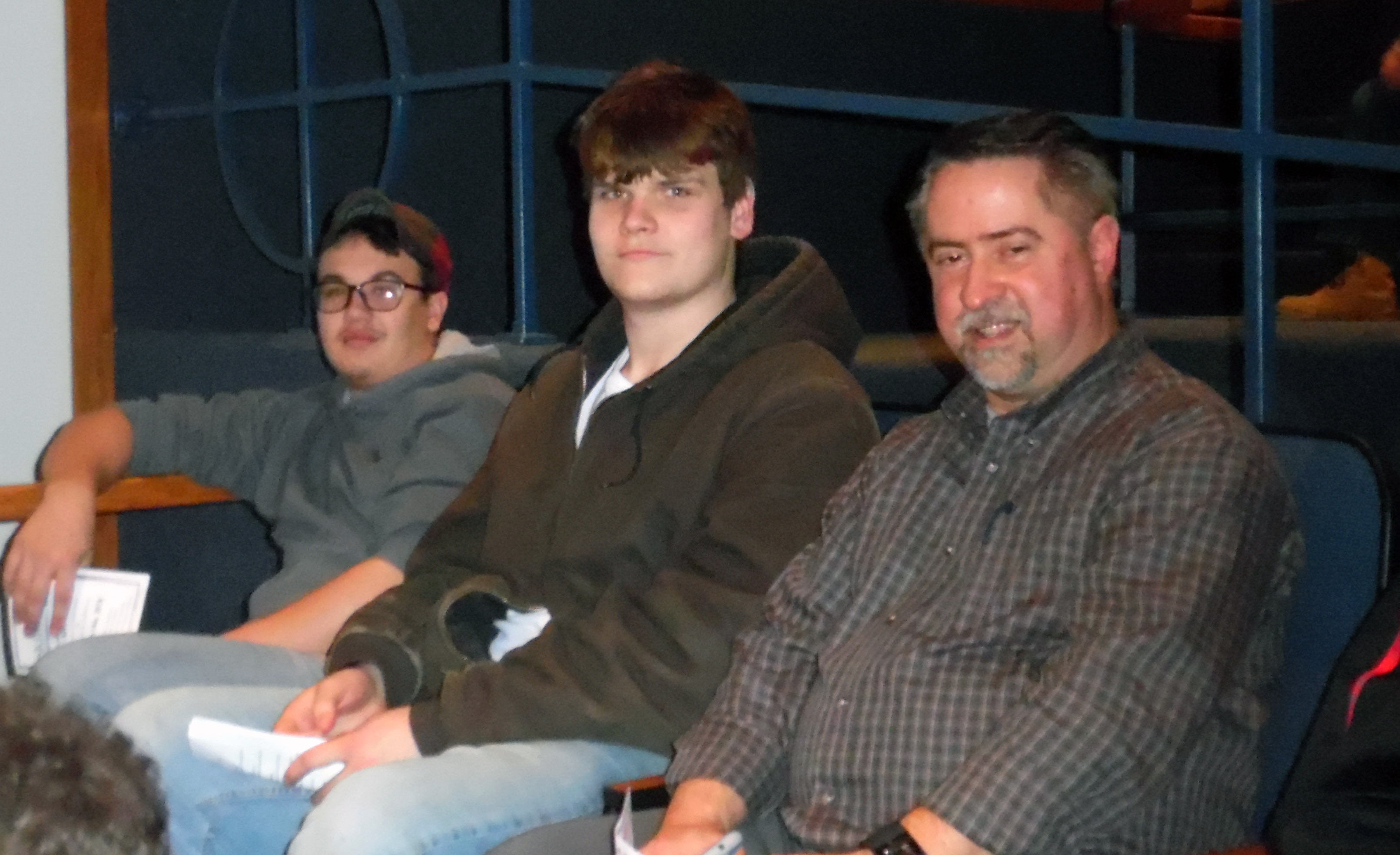 Sawyer, center, sits with two other in auditorium chairs.