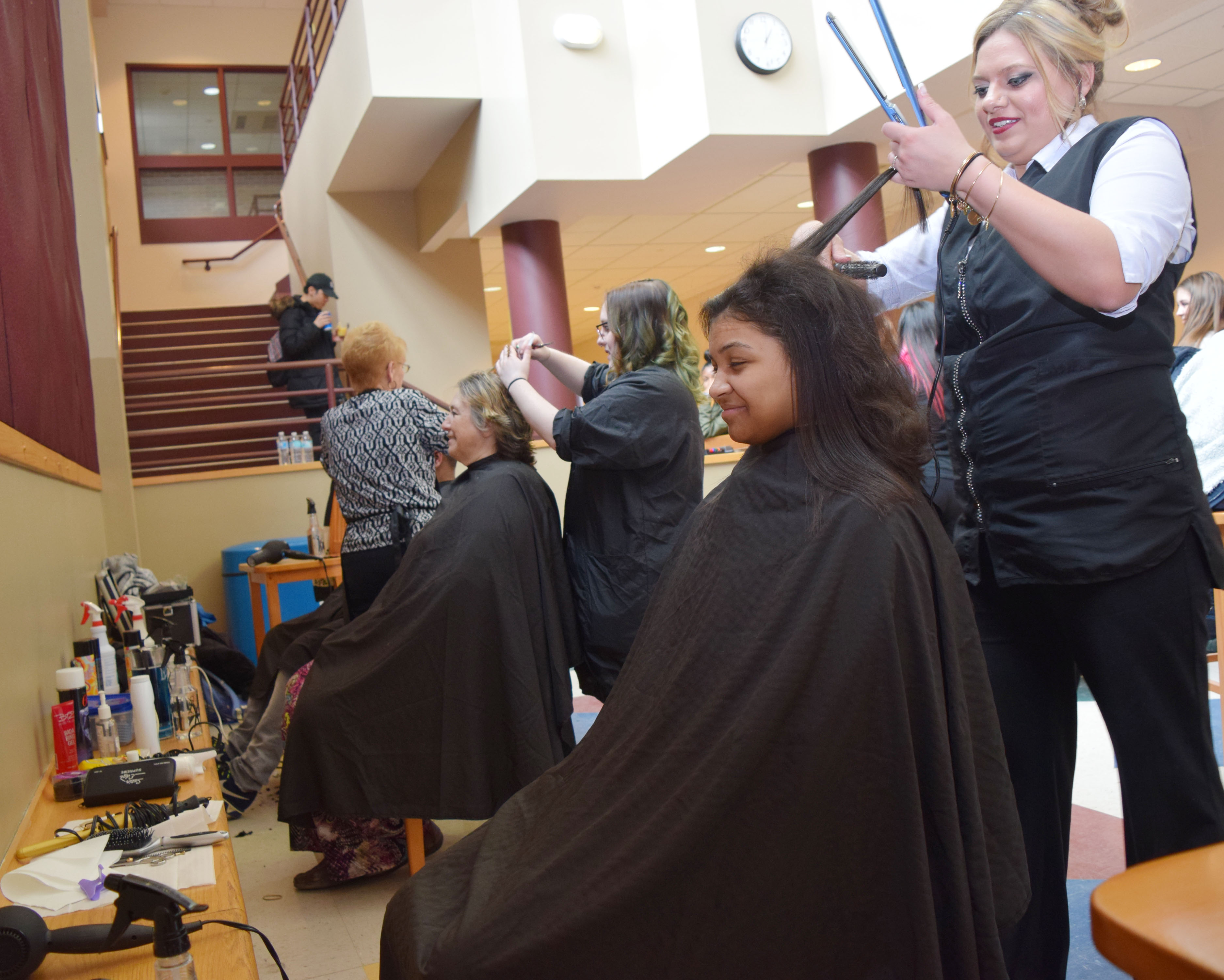 A student costemologist cuts a student's hair.