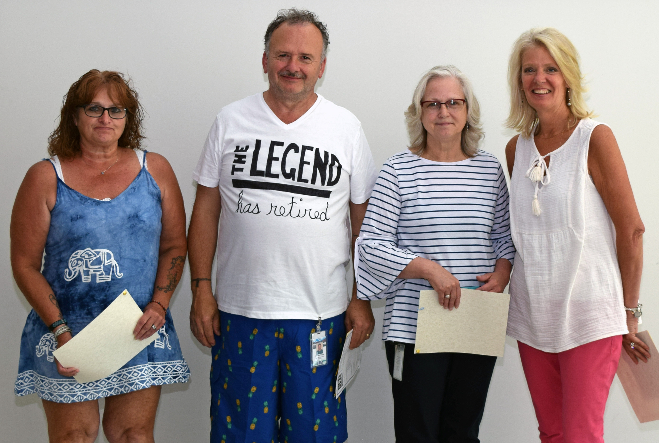 four people stand in a row smiling for a photo