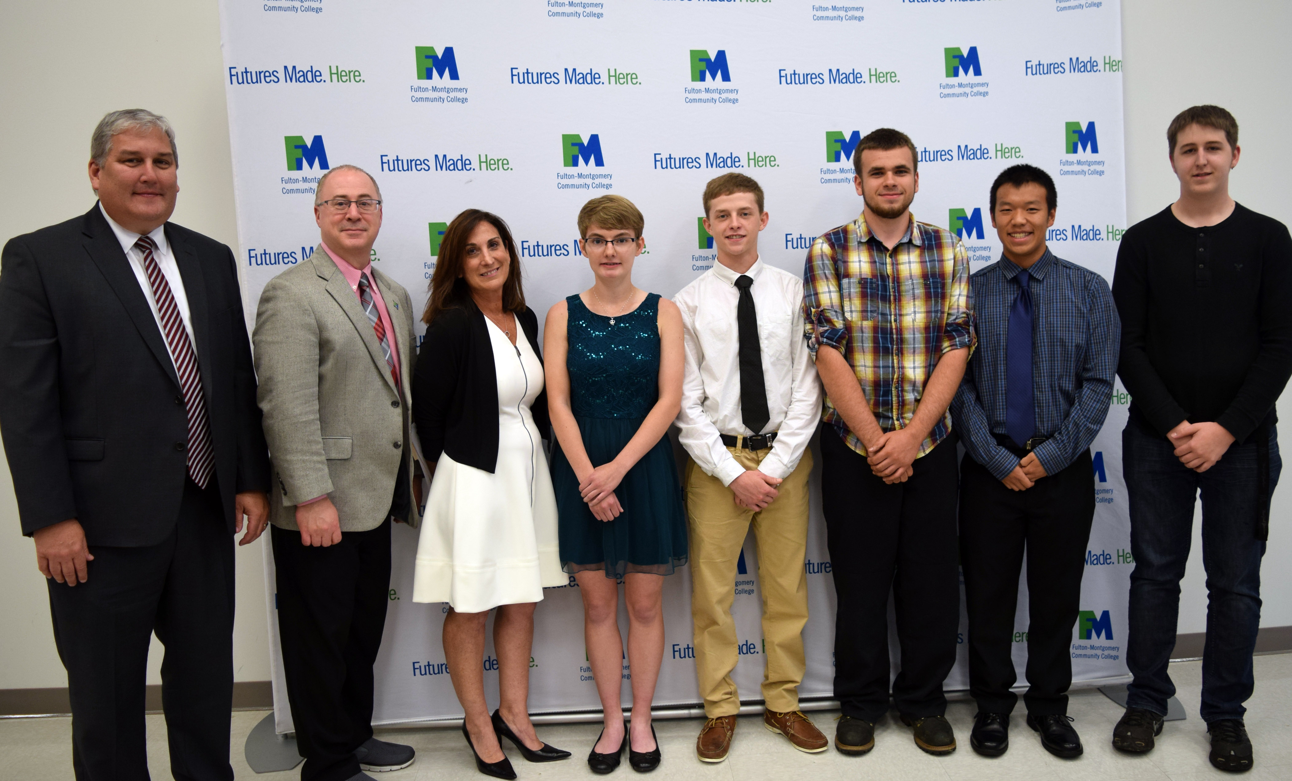 College and school administrators stand in a row posing for a photo. 