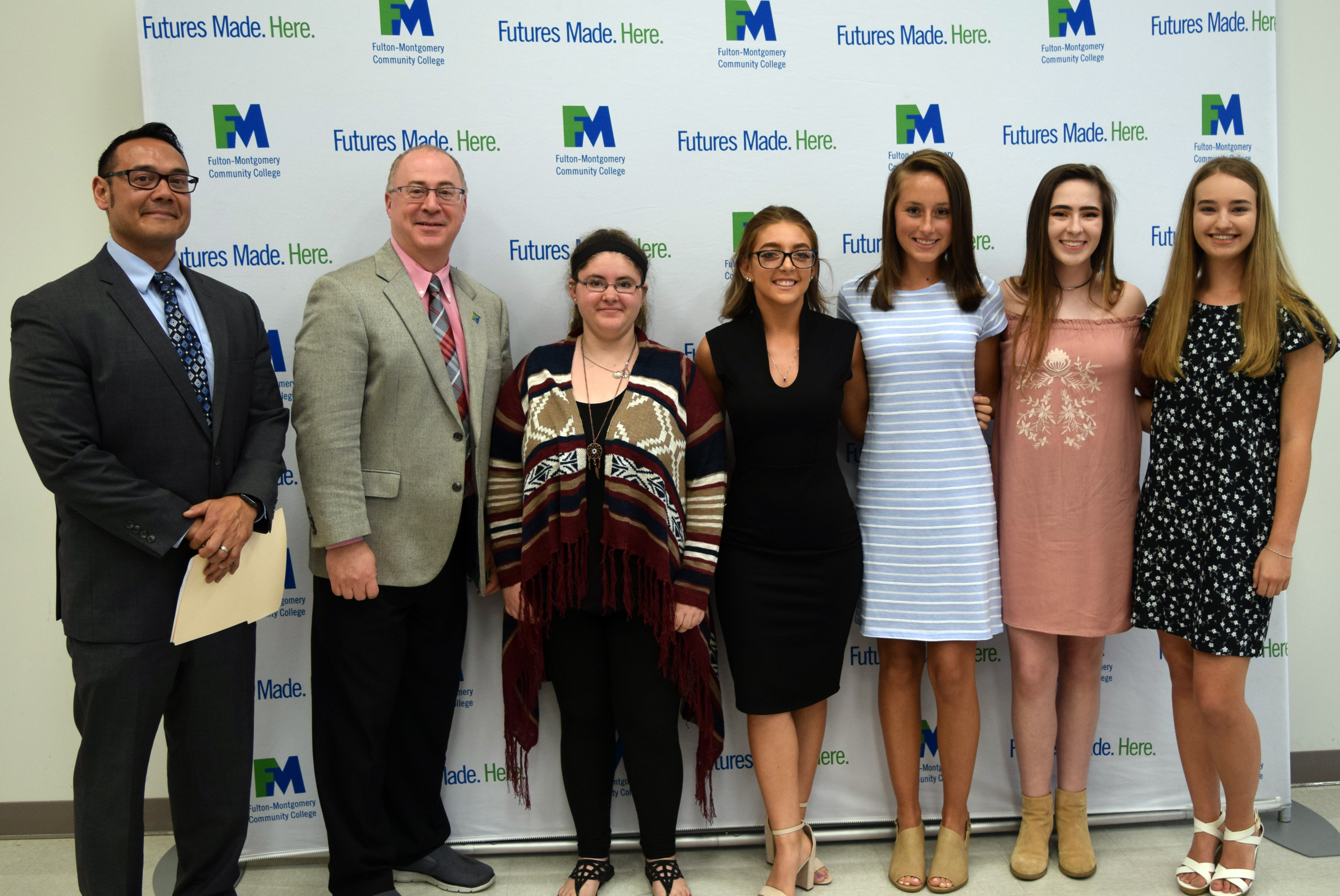 College and school administrators stand in a row posing for a photo. 