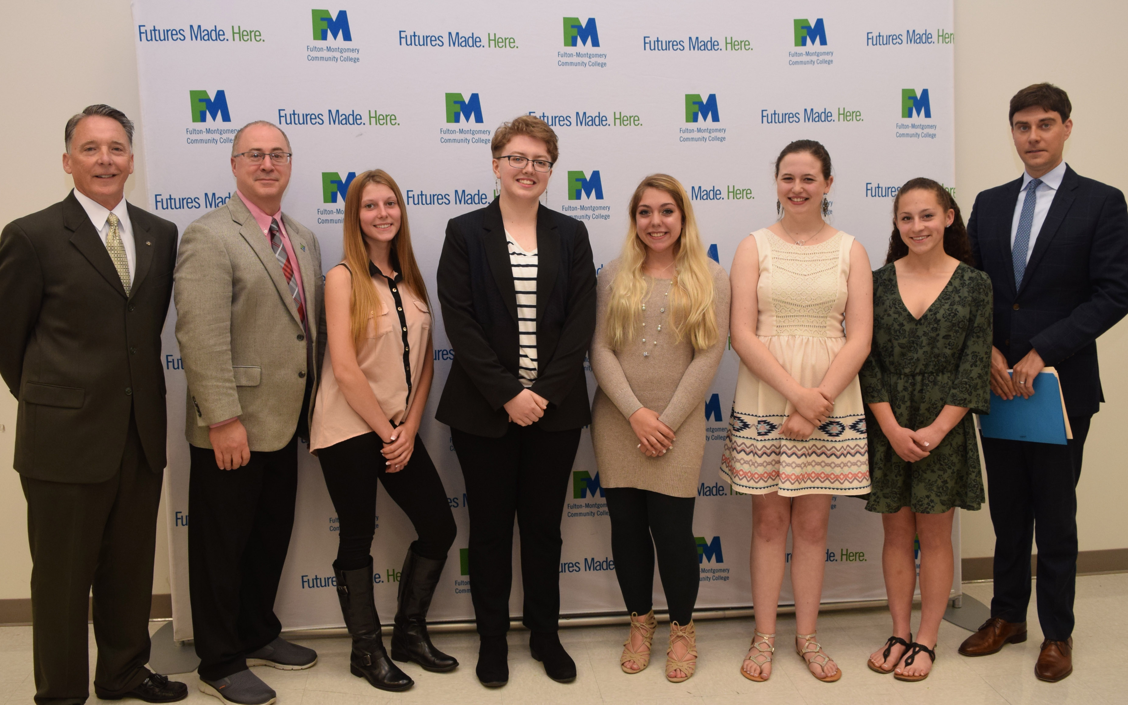 College and school administrators stand in a row posing for a photo. 