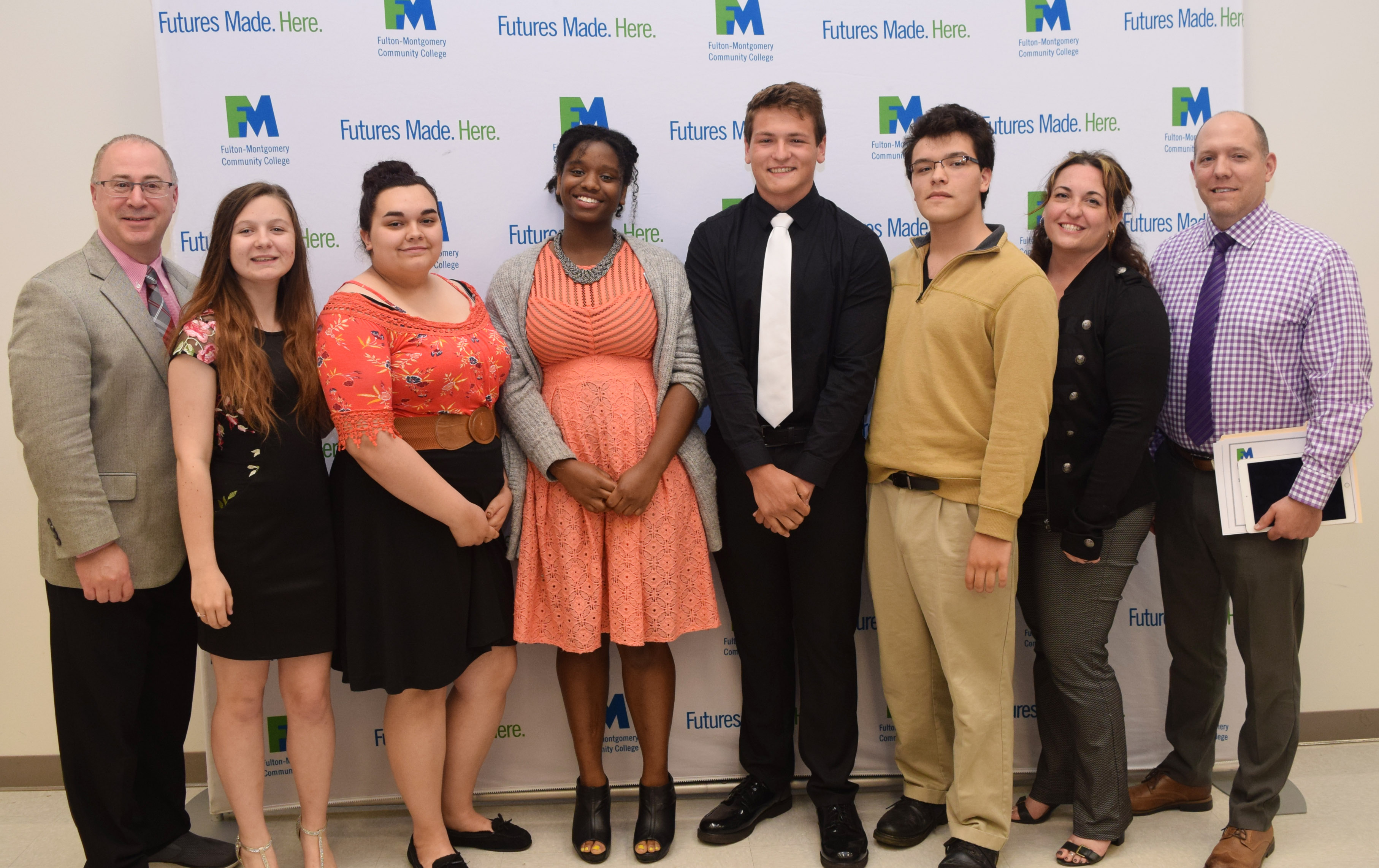 College and school administrators stand in a row posing for a photo. 