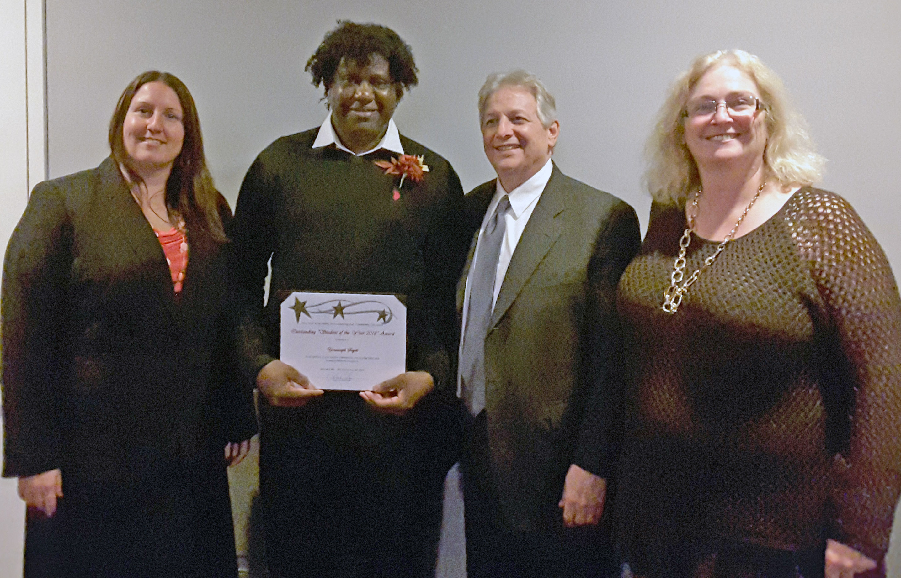 Youssouph holds a certificate and stands with three people.