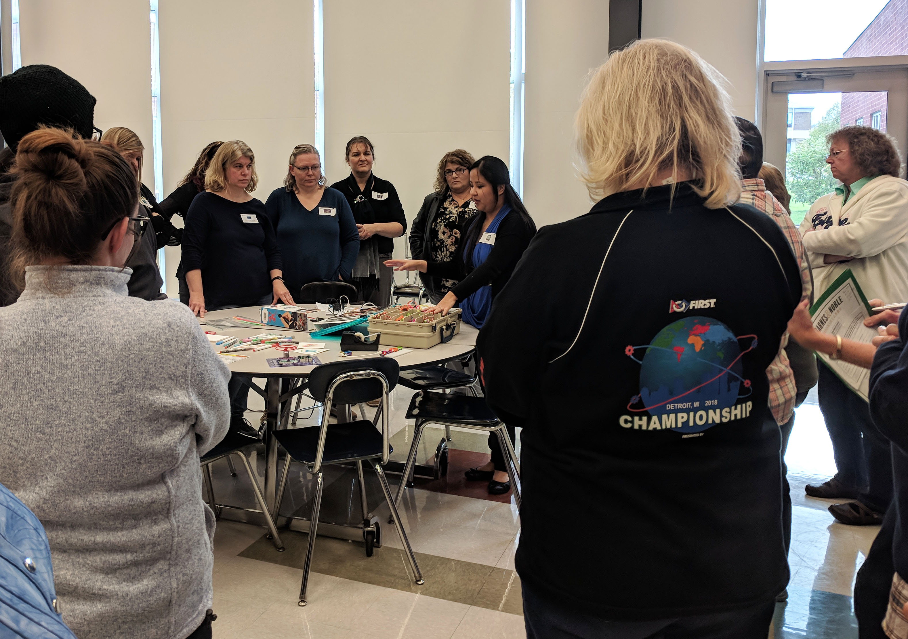 A Barnes and Noble representative stands next to a table covering in makerspace material as she speaks with gathered librarians.