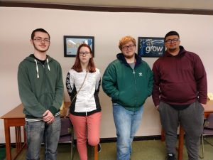 Four of the five students selected for membership into Phi Theta Kappa pose in the library.