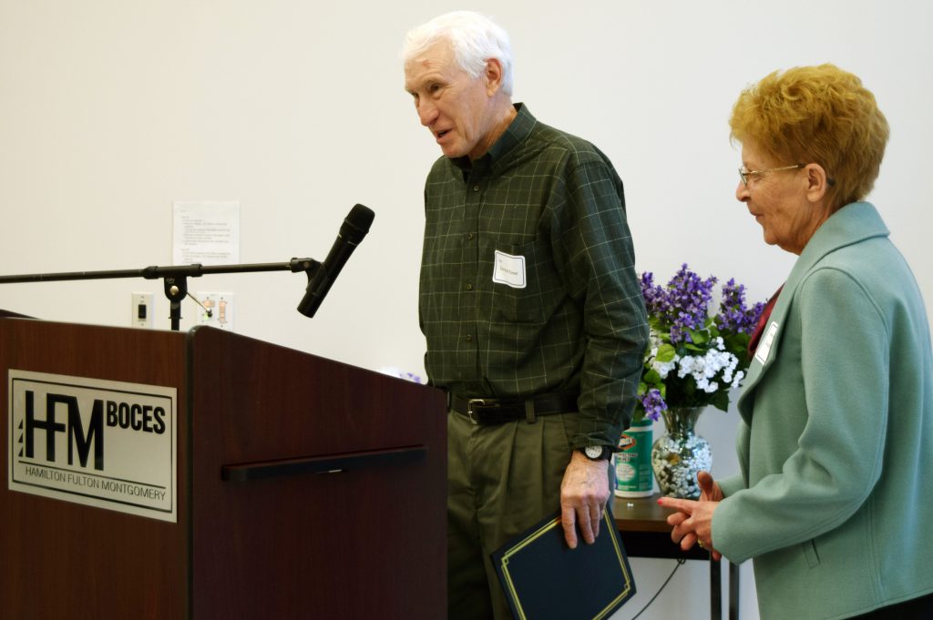 Reese stands at a podium with the board president next to him.