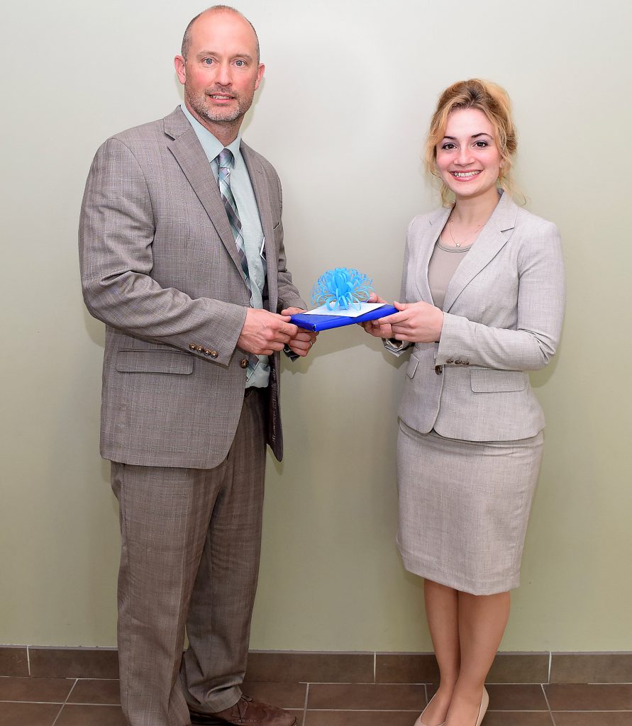 Kraemer and Cordts pose for a picture holding a gift presented to Kraemer.