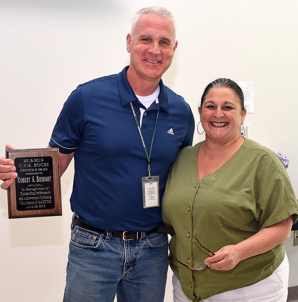 Boshart holds a wooden plaque and poses for a photo with Anita Murphy.