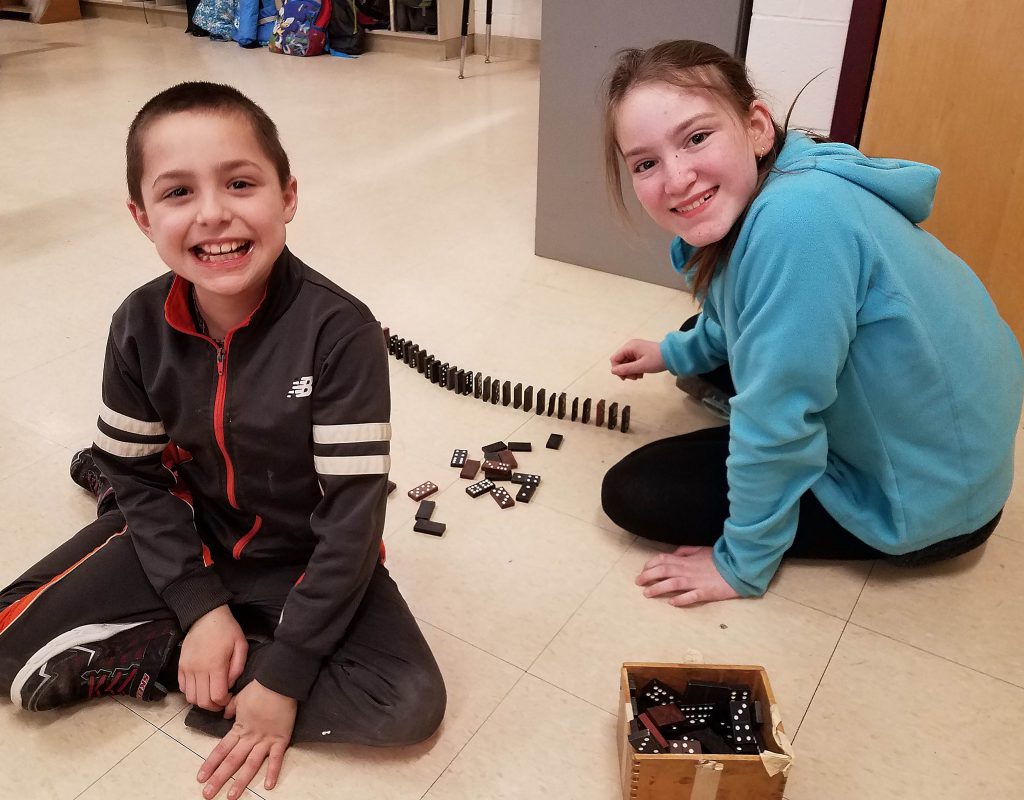 Two students set up Dominoes to knock down.