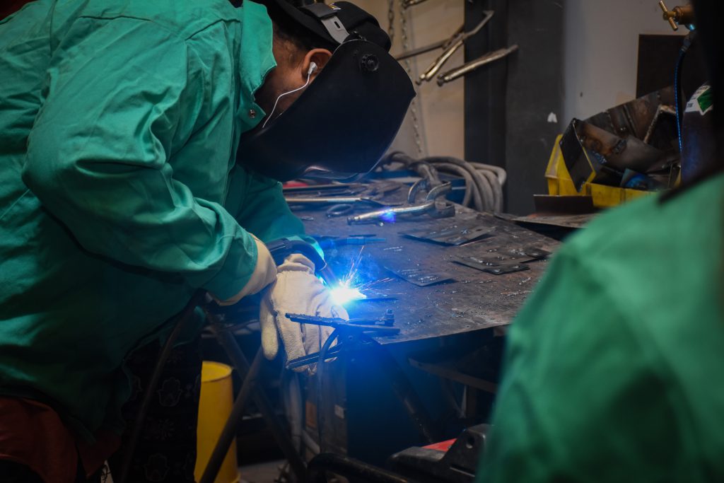 A student in protective gear uses welding equipment