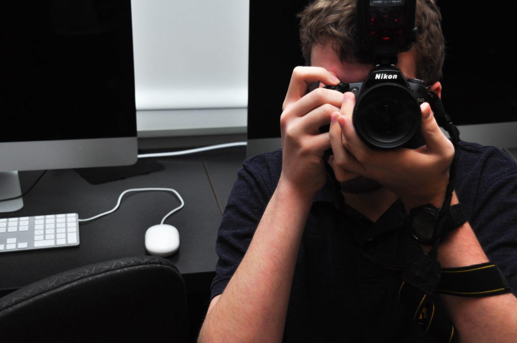 A student looks through a camera pointed to the viewer.