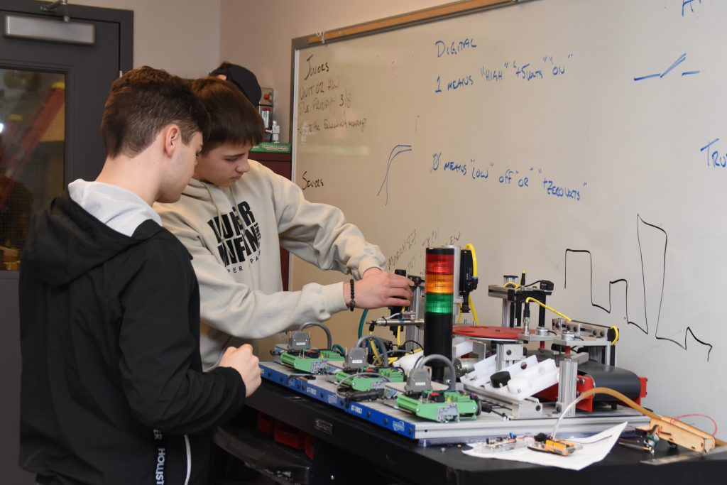 Two students work on a robotics display