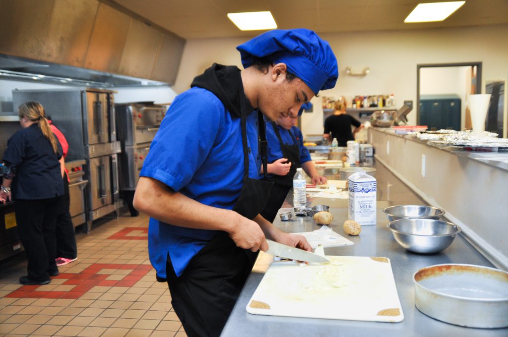 A student cuts on a cutting board