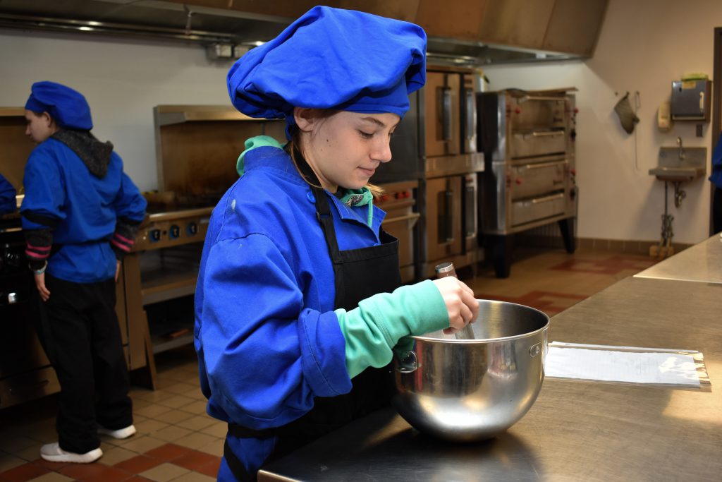 A student stirs in a metal bowl