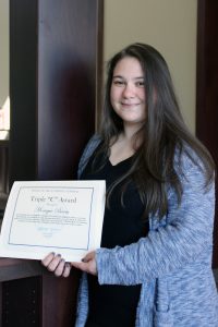 Monique Beam holding her Triple C Award certificate