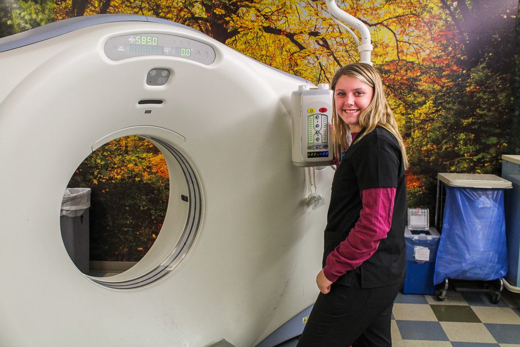 A student poses near an imaging machine