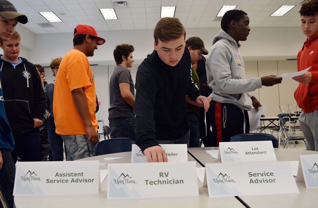 A students takes job application from a pile on a table.