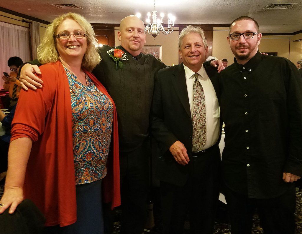 Four people pose with their arms around each other.