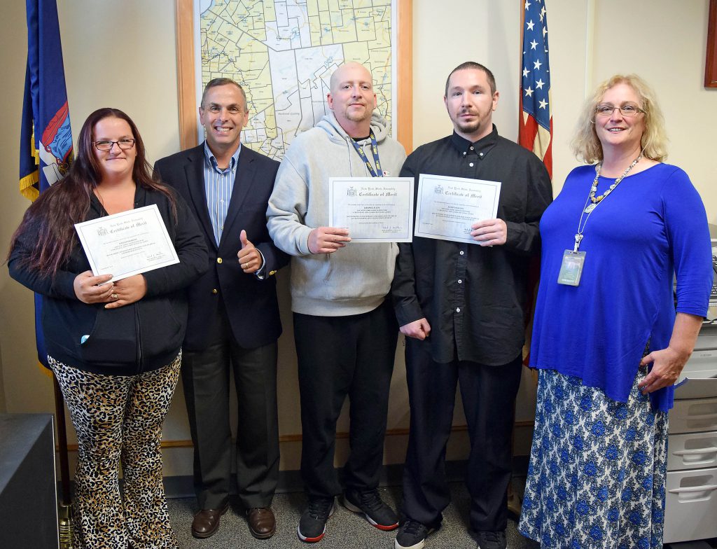 The three honorees hold certificates standing next to the assemblyman and the adult education coordinator.
