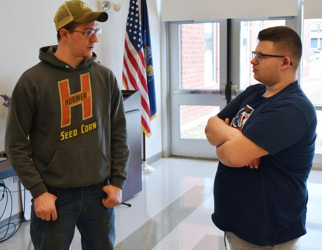 Two people stand next to each other talking