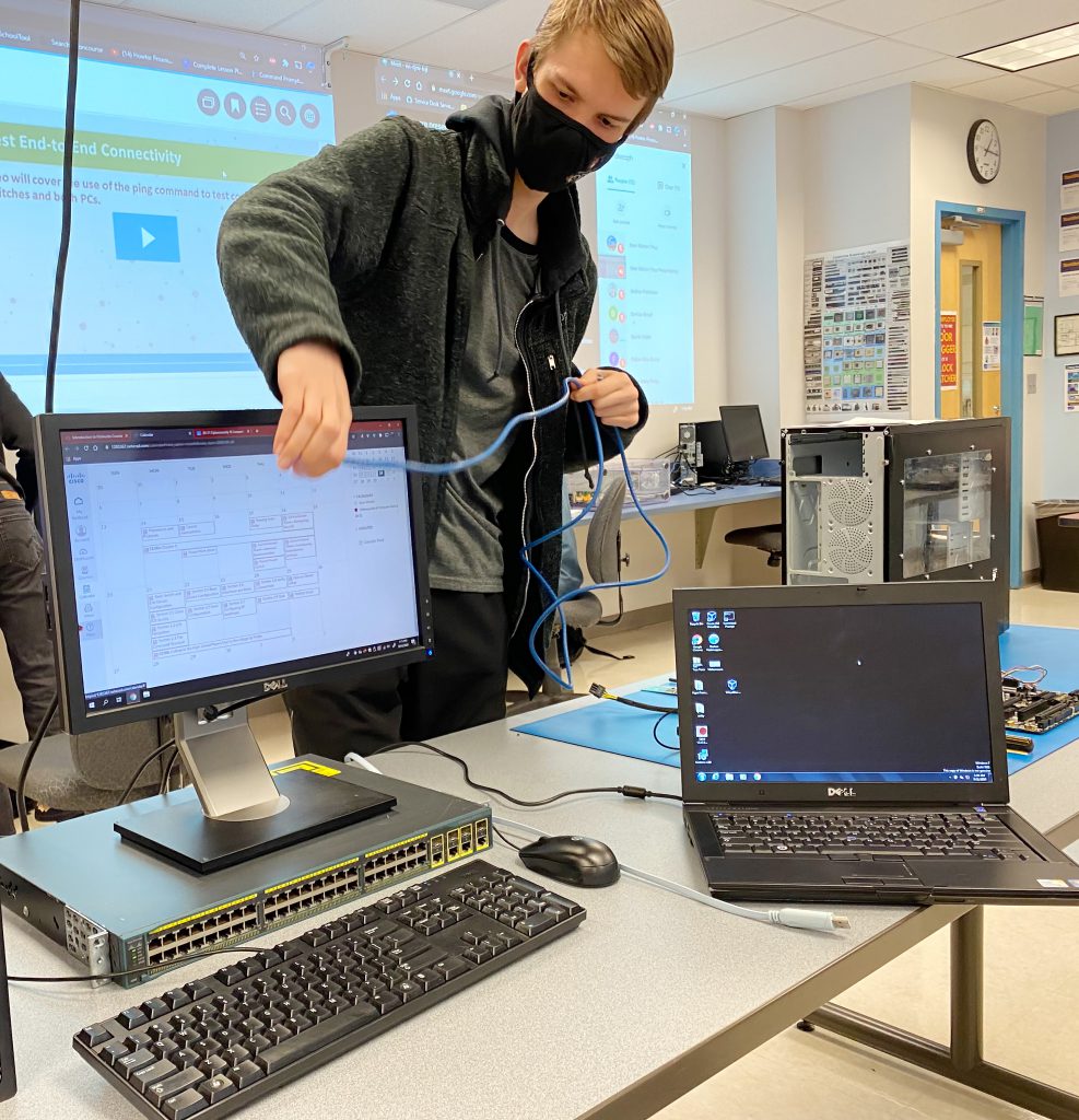 A student connects computers with a cable