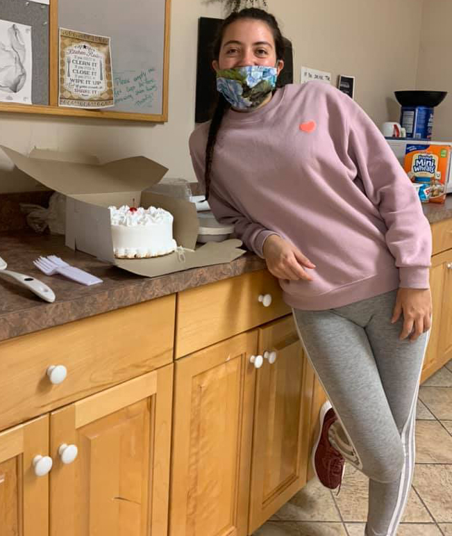 An adult student poses with a cake.