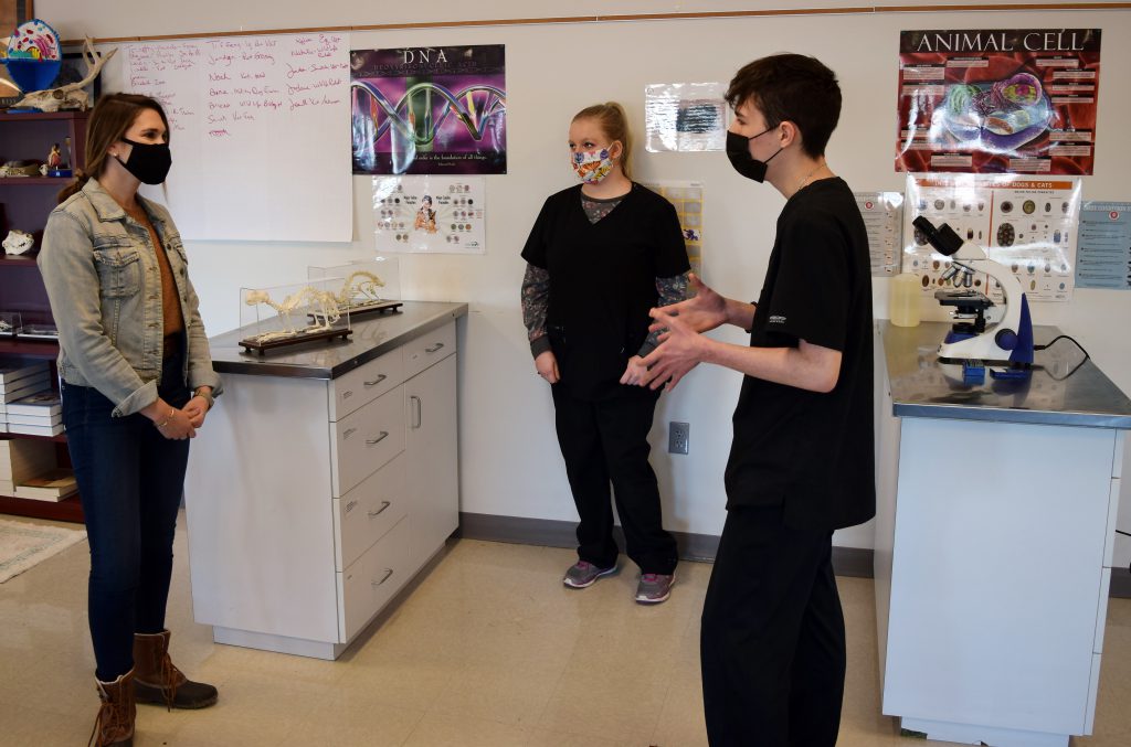 two Vet and Animal Science students speak with the senator in the program's lab. A microscope and small animal skeletons are in the background.
