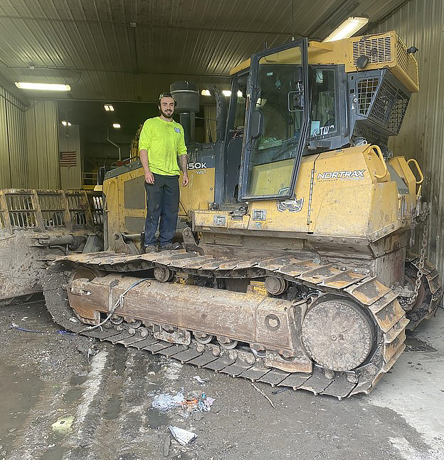 photo of David Malagisi standing on a bulldozer in the Fulton County Solid Waste garage
