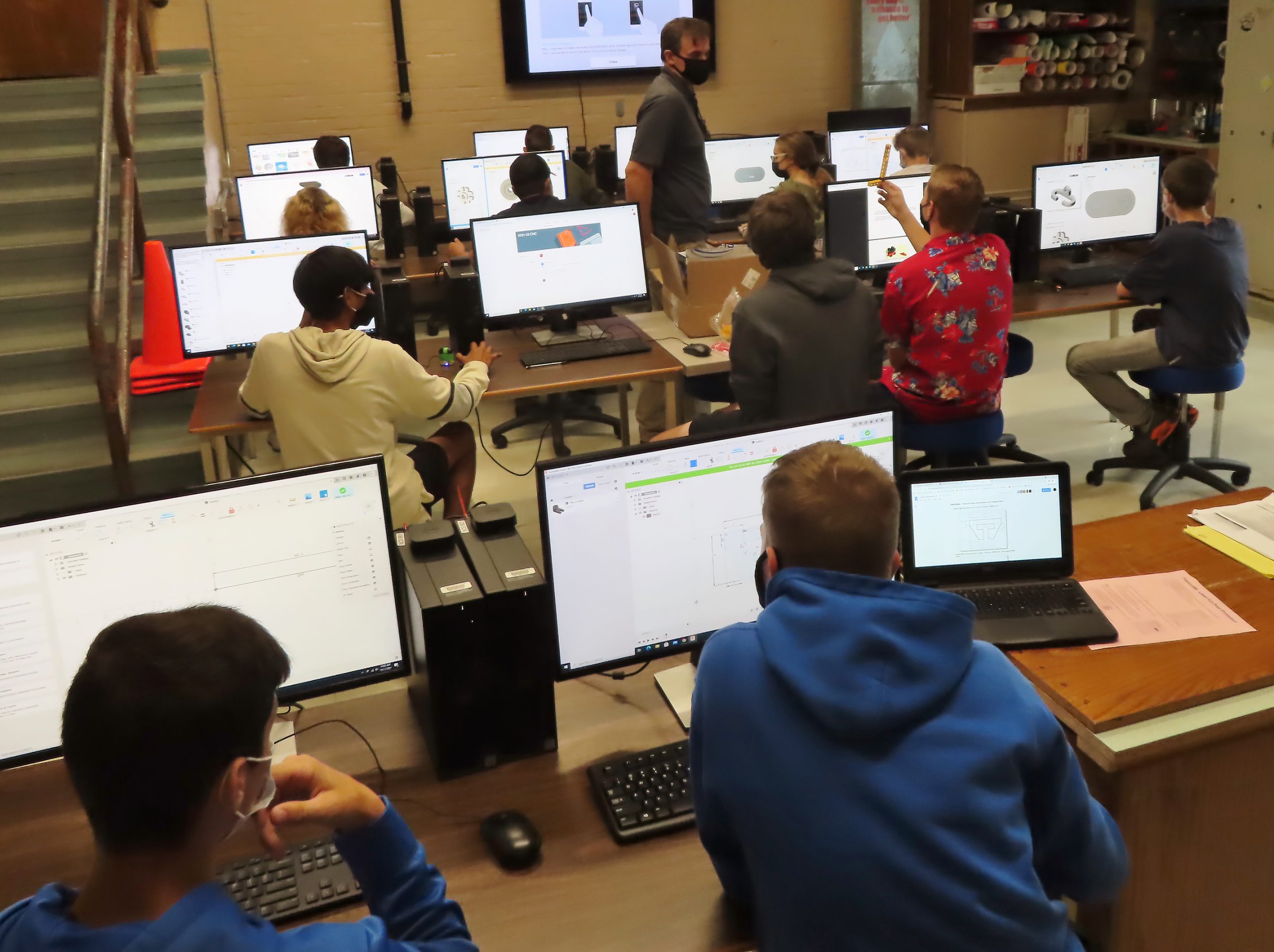 students work at computers with the teacher in front of the room