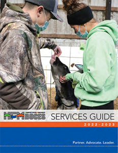 photo of printed services guide with two students feeding a cow in a barn