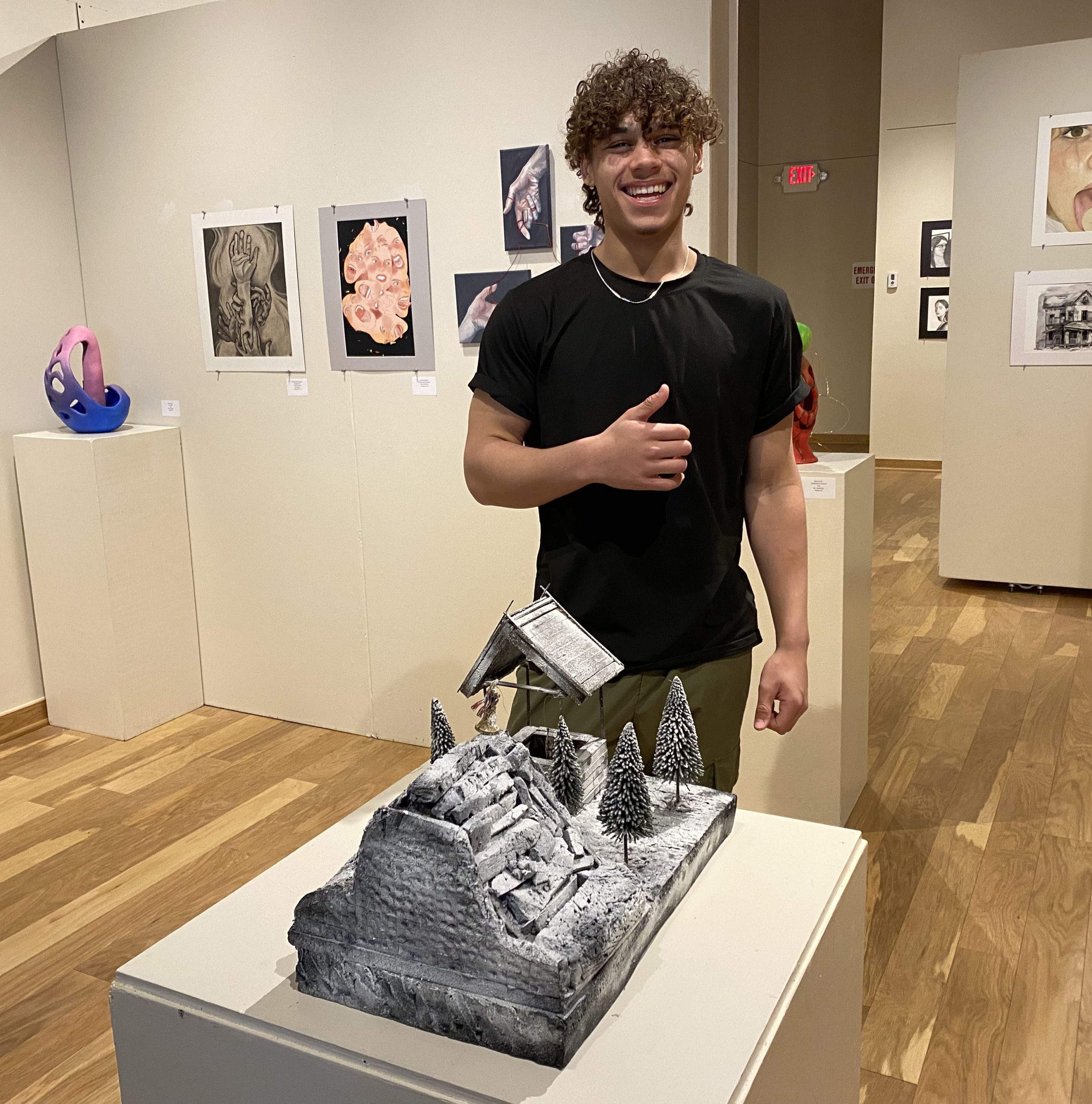 Nalzon Henry stands next to his artwork giving the thumbs up