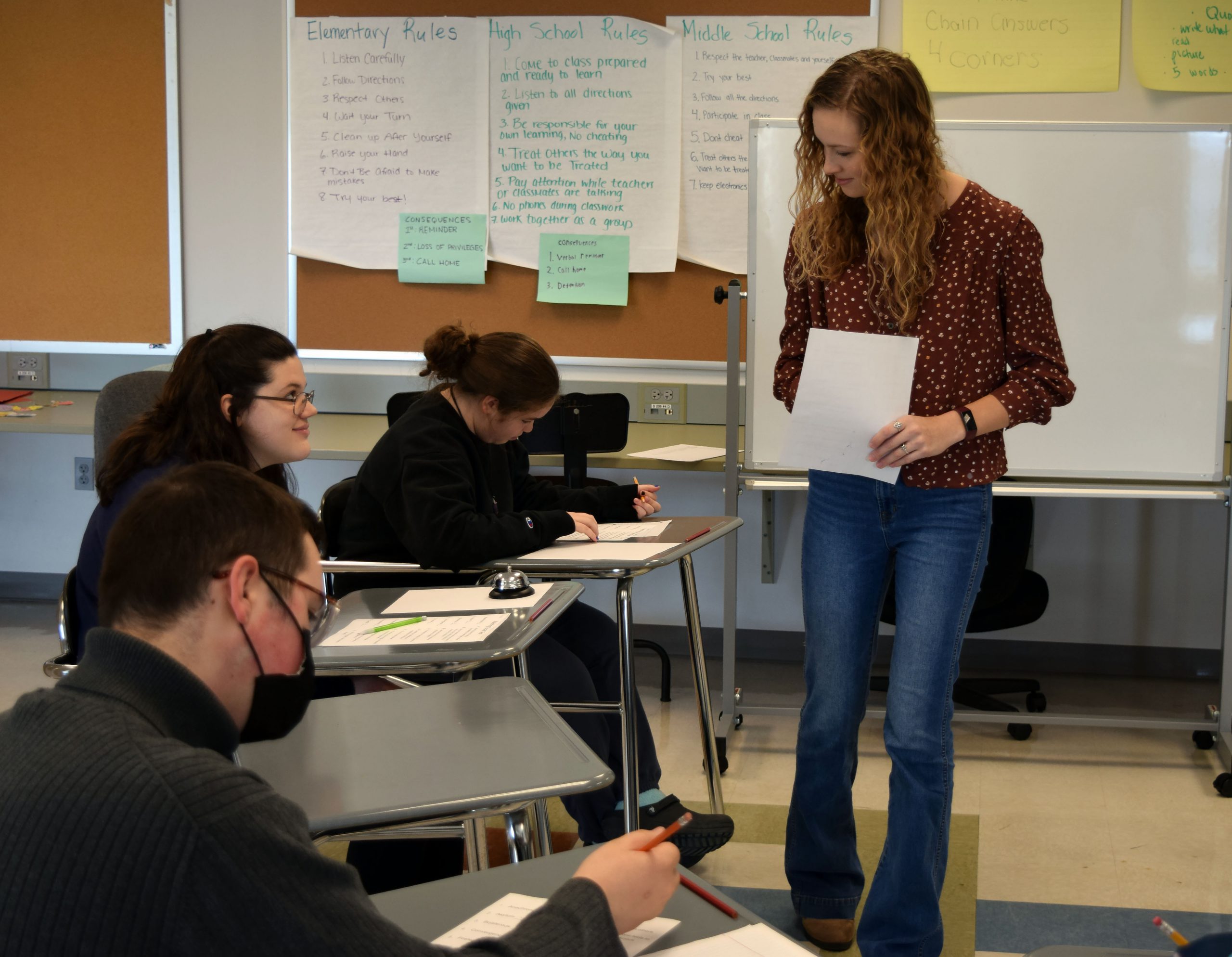 A student teacher observes students working at their desks in a classroom