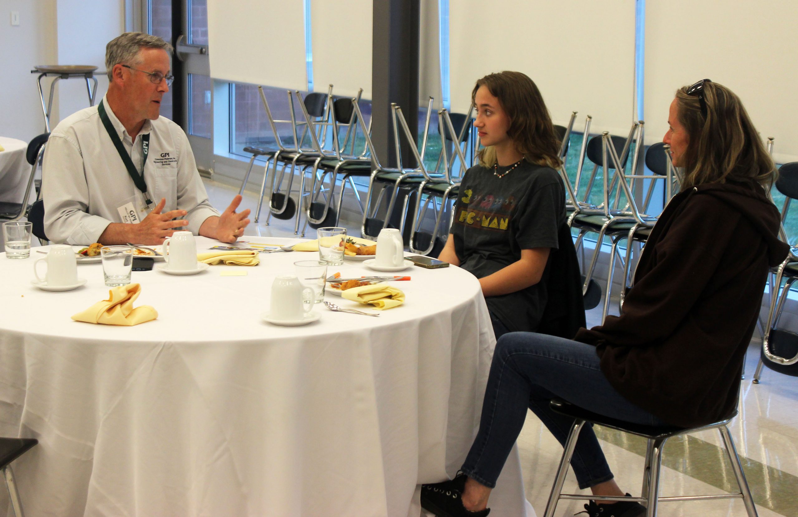 Kurt Weiskotten, an environmental scientist with GPI, sits with a student and family members at a table. 