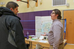 A parent speaks with a male student about the student's civilization expo project.