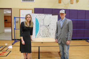 Female and male student  pose in front of their display at the civilizations expo.