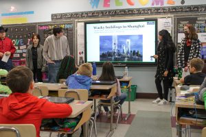 PTECH students stand in front of Promethean board and talk to elementary school students about the story book they authored and illustrated