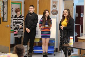 Four PTECH students stand in front of classroom facing a group of elementary school students