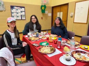 Three female PTECH students enjoying their Thanksgiving meals