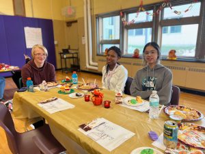 Happy PTECH students smiling for the camera while seated enjoying a Thanksgiving meal together