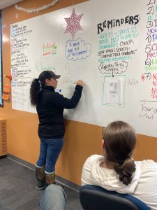 A student is writing on a whiteboard in front of the class