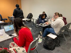 A group of students sits at desks in a classroom completing work