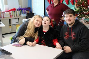 A female student sits between her guardians while waiting to meet Santa during his visit to Meco Academy