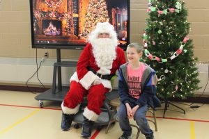 A students sits next to Santa Claus during his visit to Meco Academy
