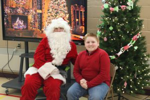 A students sits next to Santa Claus during his visit to Meco Academy