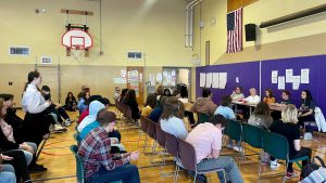 students sit in the gymnasium while listening to the panel of professionals discuss what it takes to succeed in the medical/health field.