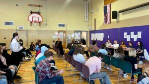 students sit in the gymnasium while listening to the panel of professionals discuss what it takes to succeed in the medical/health field.